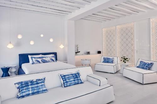 a white bedroom with a bed and a couch and chairs at Katikies Mykonos - The Leading Hotels of the World in Agios Ioannis Mykonos