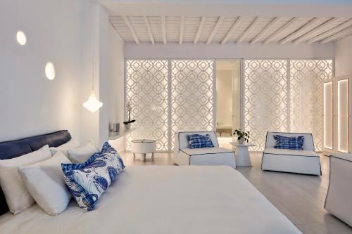 a white bedroom with a large bed and two chairs at Katikies Mykonos - The Leading Hotels of the World in Agios Ioannis Mykonos