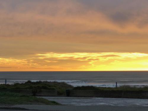 a sunset over the ocean on a beach at Otaki Beachfront Getaway in Otaki Beach
