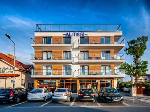 a building with cars parked in a parking lot at Al Mare - Apartamenty i pokoje in Sarbinowo