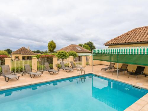 a swimming pool with chairs and a building at Two comfortable houses with swimming pool near Monbazillac and Bergerac in Saint-Nexans