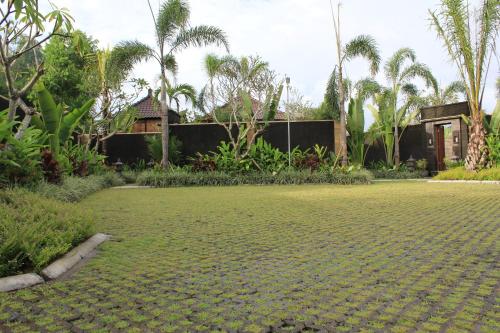 a garden with palm trees and a house at Askara Villa in Canggu