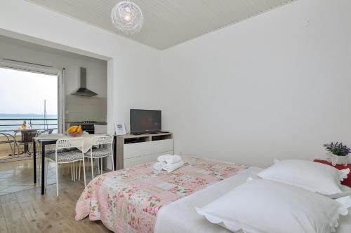 a white bedroom with a bed and a dining room at Pink in Tučepi