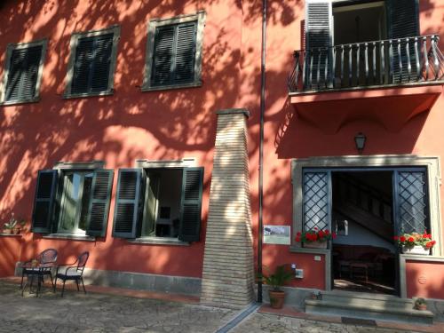 a red building with black shutters and tables and chairs at Vigna dell'Agrifoglio - Bed and Breakfast in Velletri