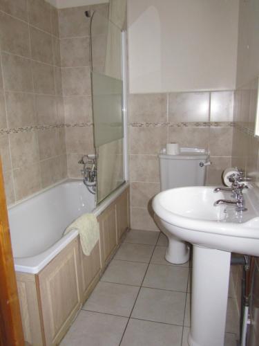 een badkamer met een wastafel, een bad en een toilet bij Briarwood Cottage in Thorpe Market