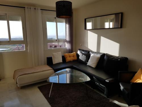 un soggiorno con divano nero e tavolo in vetro di Residential ALAZAN a Mijas Costa
