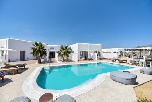 a large swimming pool with chairs and a building at Queen Boutique Suites in Mýkonos City