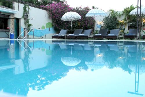 uma piscina com cadeiras e guarda-sóis ao lado de um edifício em Hotel Surya, Kaiser Palace em Varanasi