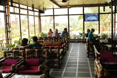 een groep mensen die in stoelen in een restaurant zitten bij Hotel Surya, Kaiser Palace in Varanasi