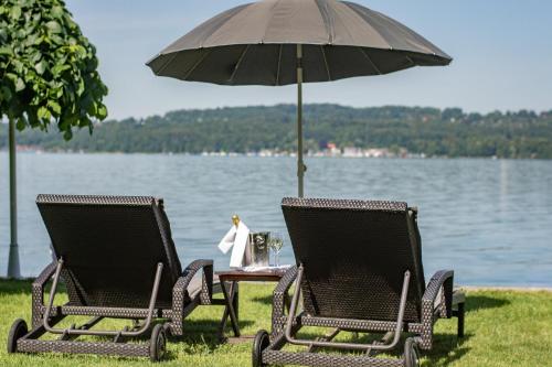 two chairs and a table with an umbrella at Seehotel Leoni in Berg am Starnberger See