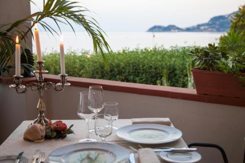 a table with plates and wine glasses and a view of the water at Park Hotel Silemi in Letojanni