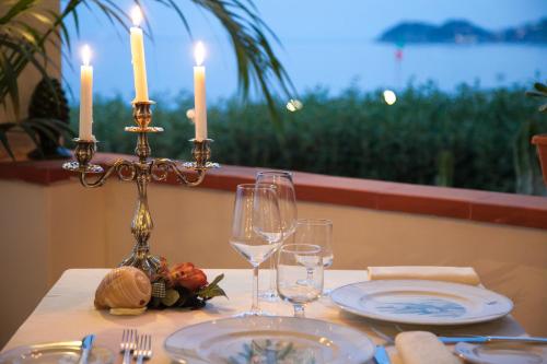 a table with two candles and plates and wine glasses at Park Hotel Silemi in Letojanni