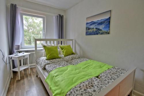 Schlafzimmer mit einem Bett mit grüner Bettwäsche und einem Fenster in der Unterkunft Ferienwohnung Eulenhof in Neustadt an der Weinstraße