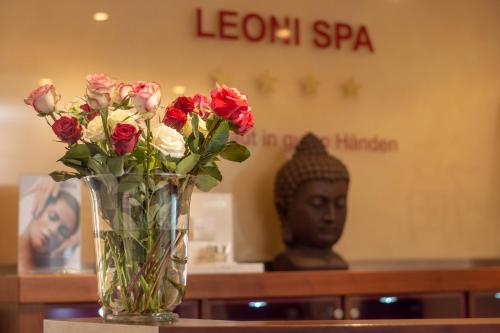 a vase of roses sitting on a table with a statue at Seehotel Leoni in Berg am Starnberger See