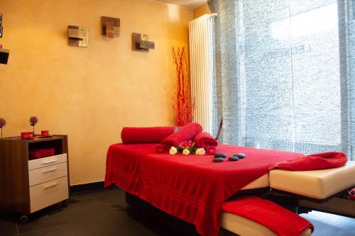 a bedroom with a red bed with a red blanket at Seehotel Leoni in Berg am Starnberger See