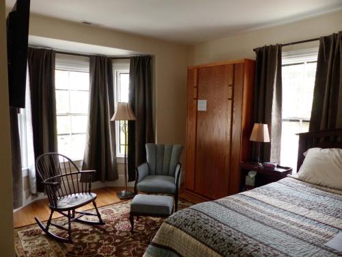 Pokój hotelowy z łóżkiem, krzesłem i oknami w obiekcie Davis Square Inn w mieście Somerville