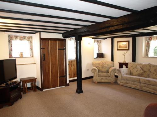 a living room with a couch and chairs and a tv at The Barn and Pinn Cottage in Sidmouth