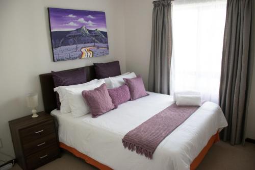 - une chambre avec un grand lit et des oreillers violets dans l'établissement Luxury 2 Bedroom Lifestyle Apartment in Golf Estate, à Roodepoort