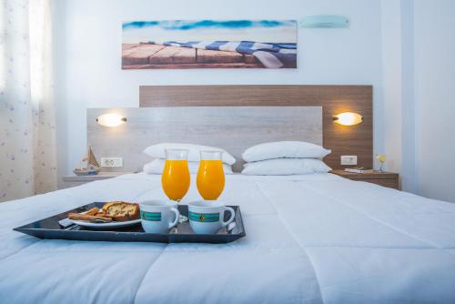 a tray with two drinks and food on a bed at Naxos Holidays in Naxos Chora