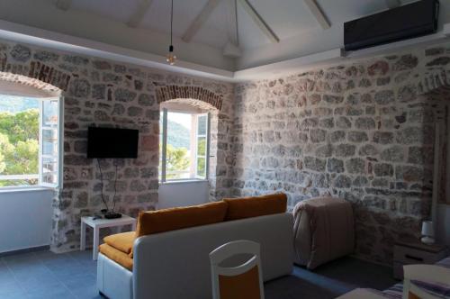 - un salon avec un canapé et des murs en briques dans l'établissement Sunny Port Apartment & Rooms, à Perast
