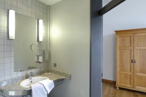 a bathroom with a sink and a mirror at Hotel Mutterhaus Düsseldorf in Düsseldorf