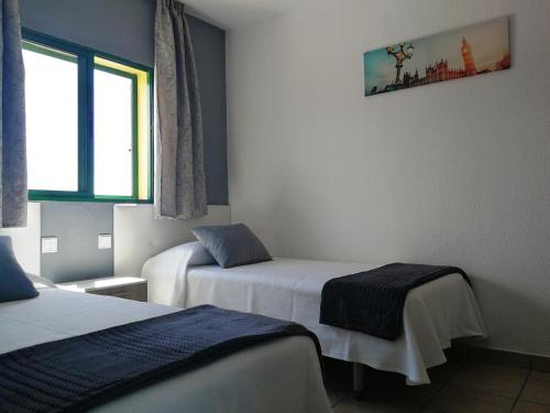 ein Hotelzimmer mit zwei Betten und einem Fenster in der Unterkunft HUELLA CANARIA Complejo LAS OLAS in Playa del Ingles
