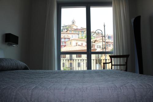 a bedroom with a bed and a large window at Hotel Il Grappolo D'Oro in Monforte dʼAlba