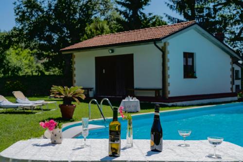 a table with wine bottles and glasses next to a pool at Lucrezia e Cesare Borgia in Borgiano