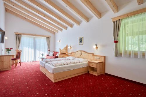 ヴァレスにあるAlpenhotel Schönwald Superiorの赤いカーペットフロアのベッドルーム1室(大型ベッド1台付)