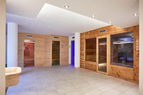 a hallway with wooden walls and a room with glass doors at Alpenhotel Schönwald Superior in Valles