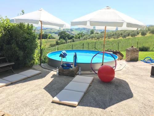 einen Pool mit Sonnenschirmen, Stühlen und einem Tisch in der Unterkunft Casa Oleandro in Fratte Rosa in San Lorenzo in Campo
