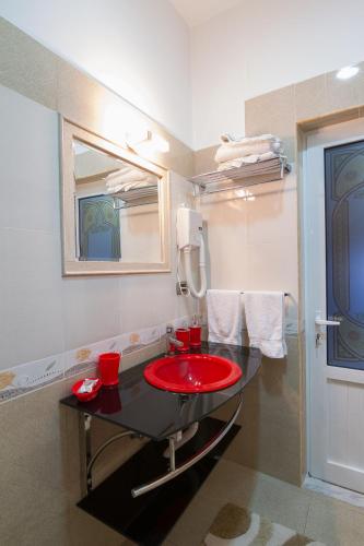 a bathroom with a red sink and a mirror at Hotel Kocibelli POOL & SPA in Korçë