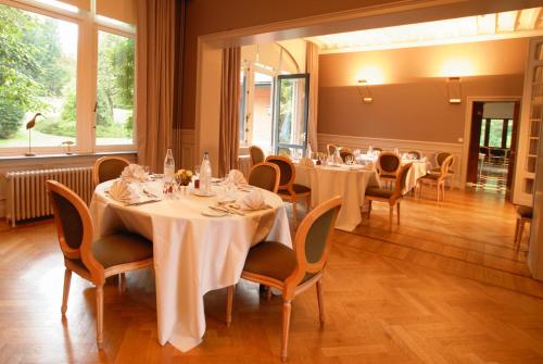 uma sala de jantar com mesas e cadeiras brancas em Martin's Manoir em Genval