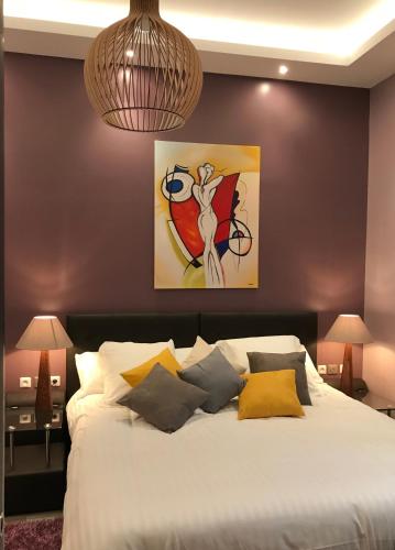 une chambre avec un lit avec un tableau sur le mur dans l'établissement NUMA BLANC 300 M PALAIS DES FESTIVALS, à Cannes