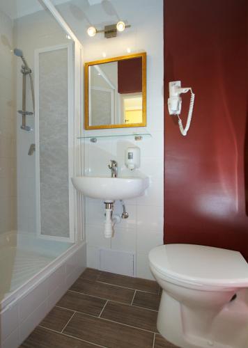 a bathroom with a sink and a toilet and a mirror at Teátrum Boutique Hotel in Győr