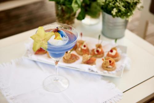 a drink in a glass on a table with a plate of food at Rouge Hotel International in Milano Marittima