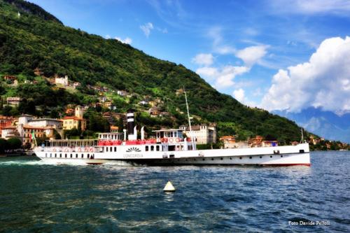 a large white boat on the water near a town at Agriturismo Cà Del Lago in Gravedona