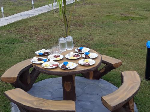 a wooden table with plates of food and glasses of water at Lagoon beach resort in Gitagun