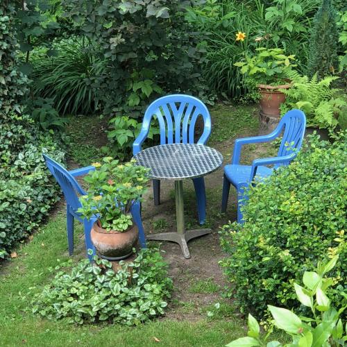 three blue chairs and a table in a garden at Linden-Jachthoorn in Lubbeek