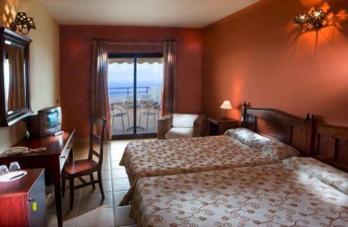 Habitación de hotel con 2 camas, escritorio y TV. en Hotel Villa El Mocanal, en Mocanal