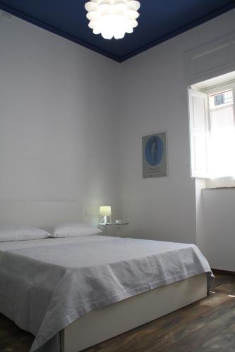 une chambre blanche avec un lit et une fenêtre dans l'établissement Le Logge, à Scicli