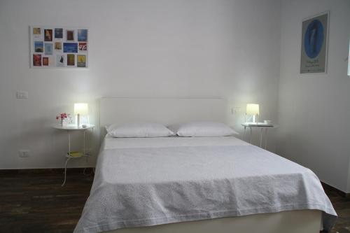a white bedroom with a bed with two lamps at Le Logge in Scicli