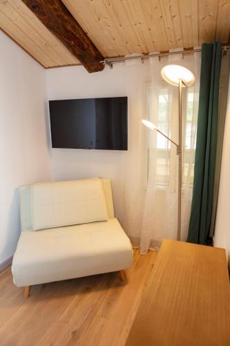 a living room with a white couch and a flat screen tv at Relais Des Alpes in Guillaumes