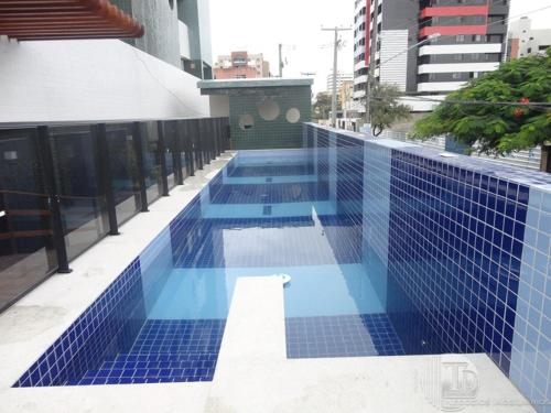 uma piscina de azulejos azuis ao lado de um edifício em Apartamento Edf Green Tower em Maceió