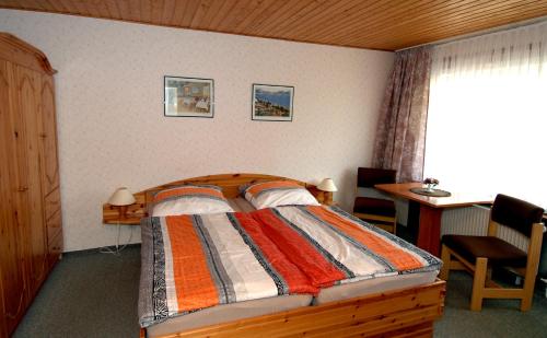 Schlafzimmer mit einem Bett, einem Schreibtisch und einem Fenster in der Unterkunft Wiedaer Hütte in Wieda