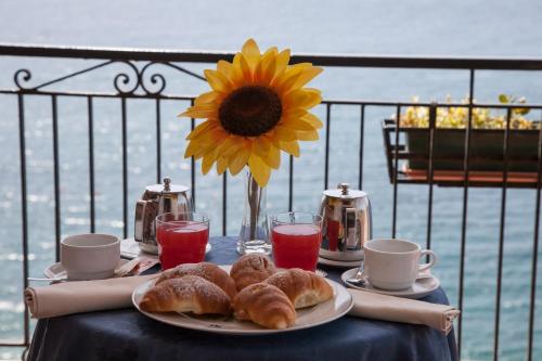 a table with a plate of pastries and a sunflower at Park Hotel Silemi in Letojanni