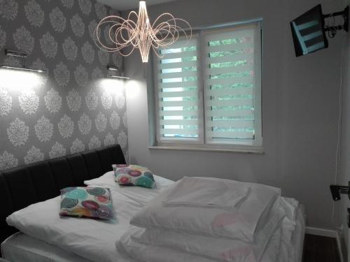 a bedroom with a bed and a window and a chandelier at Apartament Dwie Sosny in Ustronie Morskie