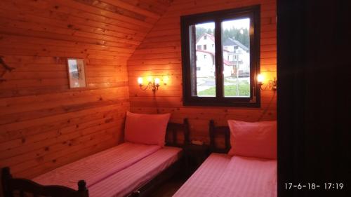 two beds in a log cabin with a window at Apartments Vila Marija in Žabljak