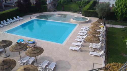 einen Blick über einen Pool mit Stühlen und Sonnenschirmen in der Unterkunft Nettuno Residence Hotel in Peschiera del Garda