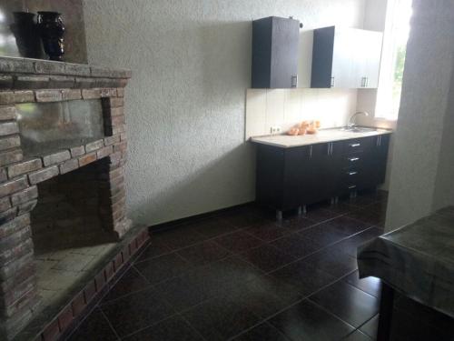 a kitchen with a brick fireplace and a sink at Guest House San Tina in Gagra